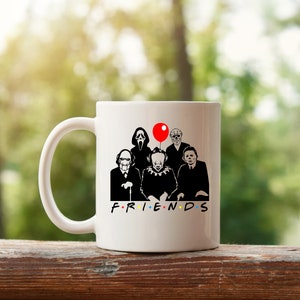 May include: White ceramic mug with a black and white illustration of horror movie characters, including a clown, a masked figure, and a man with a machete. The characters are arranged in a row and have a red balloon above them. The text "FRIENDS" is printed below the characters.