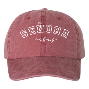 Op de afbeelding: Een rode baseballcap in vintage stijl met witte geborduurde tekst die "SENORA vibes" luidt.