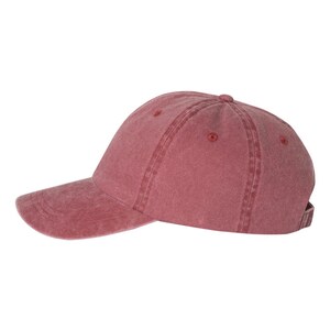 Op de afbeelding: Een effen rode baseballpet met een licht verweerde look. De pet heeft een gebogen klep en een verstelbare band.