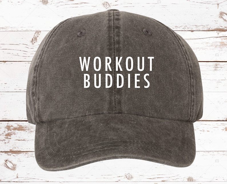 以下が含まれることがあります： 白い文字で「WORKOUT BUDDIES」と書かれたグレーの野球帽。つばがカーブしており、カジュアルな服装に適した、クラシックでアンストラクチャードなデザインです。