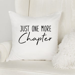 May include: White throw pillow with black text that reads "Just One More Chapter".