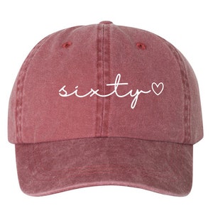 May include: A red baseball cap with the word "sixty" and a heart embroidered in white on the front.