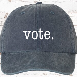 May include: A dark blue baseball cap with the word "vote" embroidered in white on the front.