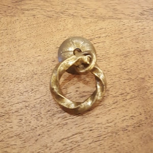 Peut inclure: Une poignée de porte en métal doré avec un anneau torsadé.