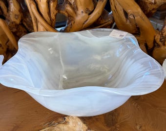 May include: A large, translucent white glass bowl with a wavy, organic rim. The bowl features a swirling, marbled pattern throughout the glass and a small rectangular white tag attached to the inner edge of the rim.