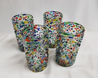 May include: Set of four clear glass tumblers with a colorful confetti pattern. The glasses are speckled with various colors, including red, blue, green, yellow, and white.