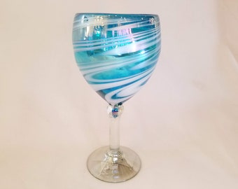 May include: A blue and white swirl glass wine glass. The glass has a clear stem and base.