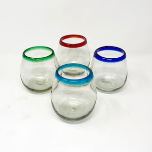 May include: Four clear, stemless drinking glasses with colorful rims. The rims are painted in green, red, blue, and turquoise. The glasses are arranged on a white background.