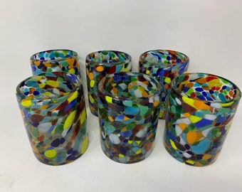 May include: Six colorful glass tumblers with a mosaic pattern. Each tumbler is made of clear glass with embedded pieces of colored glass in shades of blue, green, yellow, orange, red, and white.