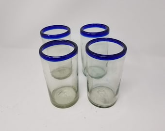 May include: Set of four clear glass drinking glasses with a blue rim.