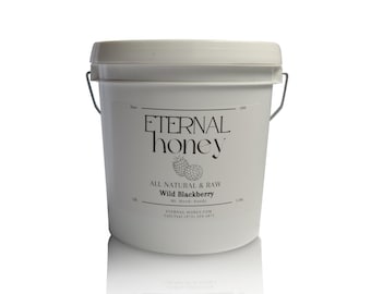 May include: A white plastic bucket with a metal handle and a lid. The label reads Eternal Honey, All Natural & Raw, Wild Blackberry, Mt. Hood-Sandy, Since 2000, eternal-honey.com, and Call/Text (971) 319-5873, featuring a graphic of two blackberries.