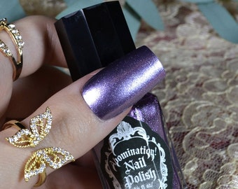 May include: A bottle of purple metallic nail polish with the label "Domination! Nail Polish" in black and white lettering.