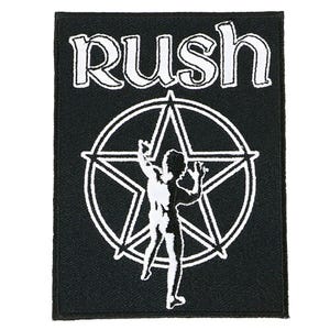 May include: Black rectangular patch featuring the band name "Rush" in white, above a white pentagram with a silhouetted figure. The patch is likely for clothing or accessories.