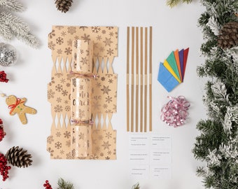 May include: A Christmas cracker kit with a gold and white snowflake design. The kit includes a cracker, a paper crown, a joke, a small gift, and a pull string.