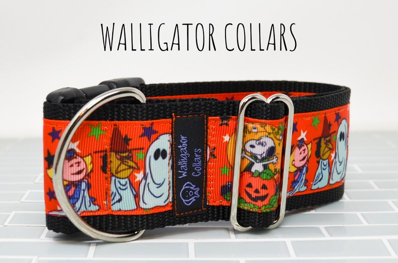 Puede incluir: Un collar de perro negro y naranja con un estampado de Halloween con personajes de la tira c&oacute;mica Peanuts. El collar tiene un anillo en D plateado y una hebilla plateada. El texto "Walligator Collars" est&aacute; impreso en una etiqueta negra unida al collar.