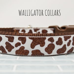 May include: A white and brown dog collar with a brown glitter cow print pattern. The collar has a brown plastic buckle.