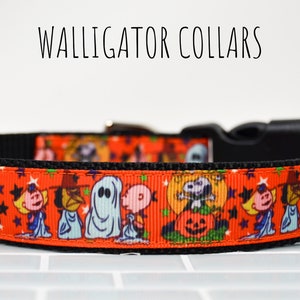 Puede incluir: Un collar de perro rojo y negro con un estampado de tem&aacute;tica de Halloween con personajes de Peanuts como Snoopy, Charlie Brown y Lucy. El collar tiene una hebilla negra y un anillo en D plateado.