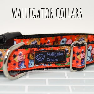 Puede incluir: Un collar de perro negro y naranja con un estampado de Halloween con personajes de dibujos animados y calabazas. El collar tiene una hebilla plateada y un clip de pl&aacute;stico negro. El texto "Walligator Collars" est&aacute; impreso en el collar.