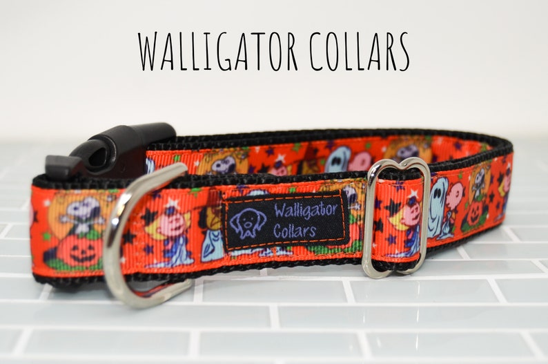 Puede incluir: Un collar de perro negro y naranja con un estampado de Halloween con personajes de dibujos animados y calabazas. El collar tiene una hebilla plateada y un clip de pl&aacute;stico negro. El texto "Walligator Collars" est&aacute; impreso en el collar.