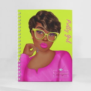 May include: A lime green spiral bound notebook with a pink and black illustration of a woman wearing green glasses and a pink sweater. The text "pretty girl" is written vertically on the right side of the notebook. The bottom of the notebook has the text "Dreamz by N.V.A."