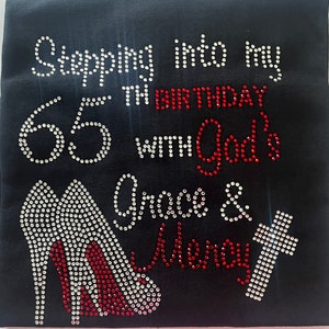 May include: Black t-shirt with rhinestones spelling "Stepping into my 65th birthday with God's Grace & Glory" with a pair of red high heels and a cross.