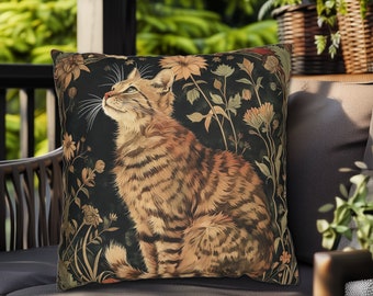May include: A decorative throw pillow with a black background featuring a detailed illustration of a tabby cat sitting in a field of flowers. The cat is looking up and has a light brown and black striped pattern. The flowers are in shades of yellow, orange, and red.
