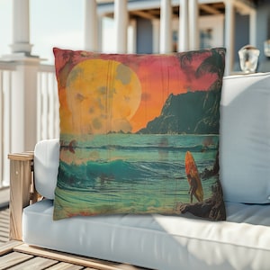 May include: A decorative throw pillow with a vintage-style image of a surfer standing on a beach at sunset. The image features a large yellow sun, blue ocean waves, and a palm tree.