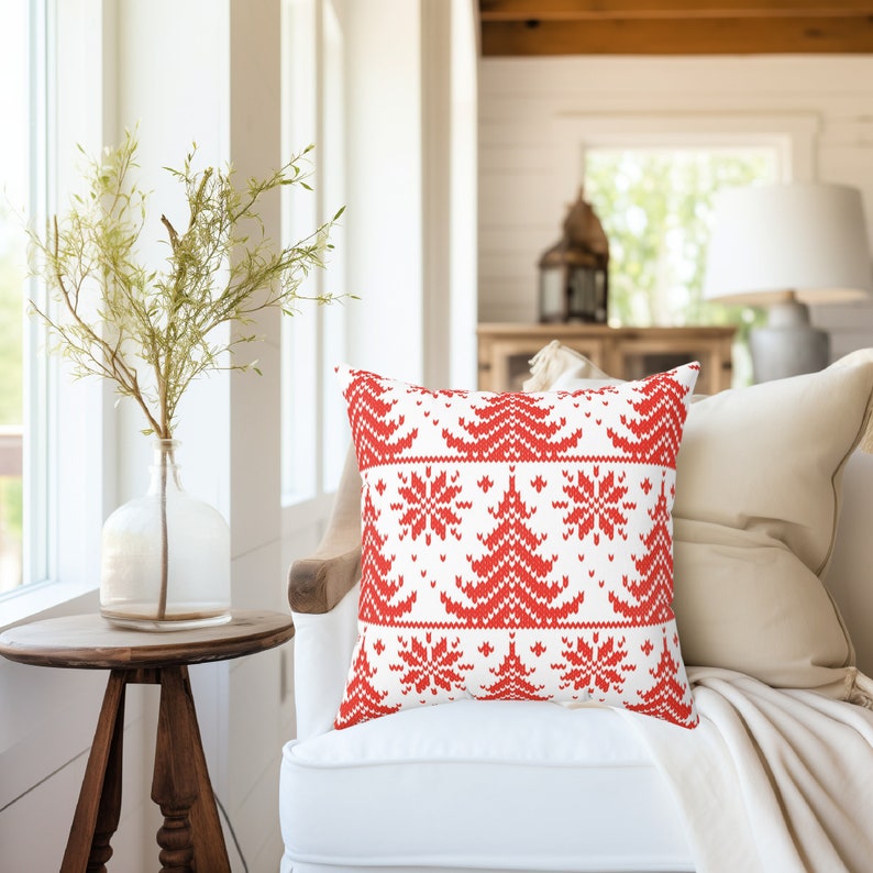 May include: Red and white throw pillow with a knitted Christmas tree and snowflake pattern. The pillow is on a white sofa with a white throw blanket.