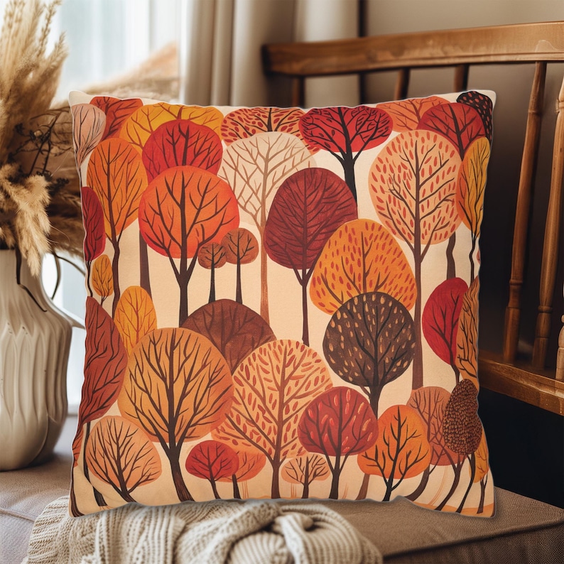 May include: A cream-colored throw pillow with a colorful autumn forest print. The pillow features a pattern of orange, red, and brown trees with white trunks against a cream background.