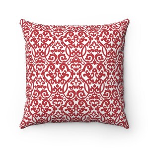 May include: Square throw pillow with a red and white damask pattern. The pillow features a repeating ornate design in a vibrant red color against a white background. The pillow is a decorative item for a bed or sofa.