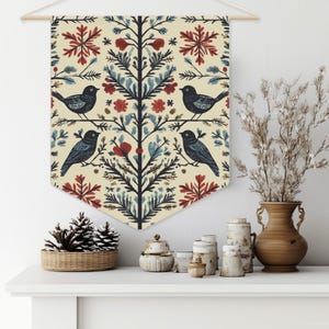 May include: A cream-coloured fabric wall hanging with a repeating pattern of stylised trees, birds, snowflakes, and flowers in shades of red, blue, and gold.