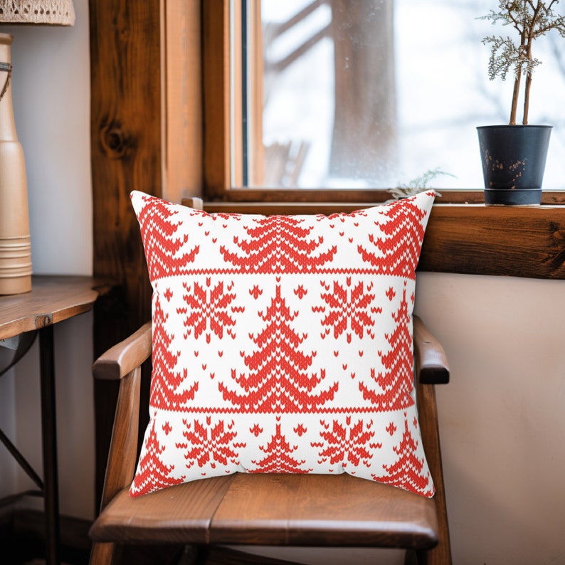 May include: Red and white throw pillow with a knitted Christmas tree and snowflake pattern.