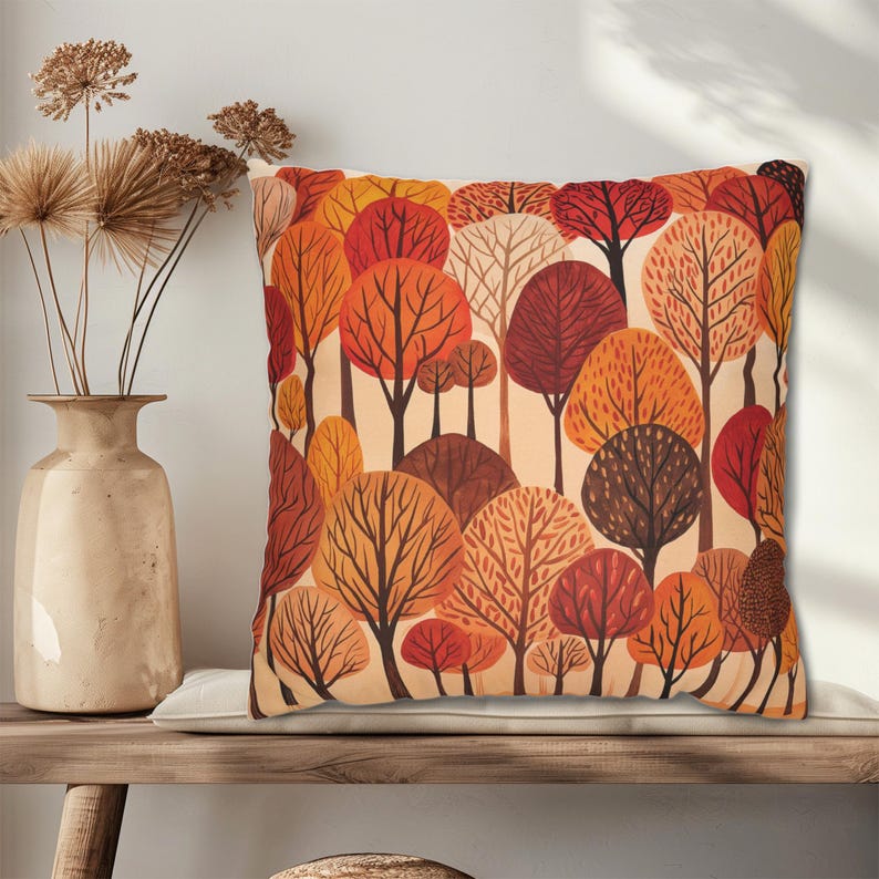 May include: A square throw pillow with a cream background and a pattern of stylized trees in shades of orange, red, and brown.