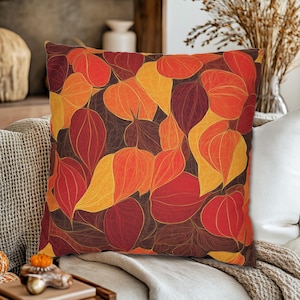 Pode incluir: Uma almofada de lançamento com um design de outono que apresenta um padrão de folhas vermelhas, laranja e amarelas. As folhas são delineadas em uma cor marrom escura e têm uma aparência texturizada.