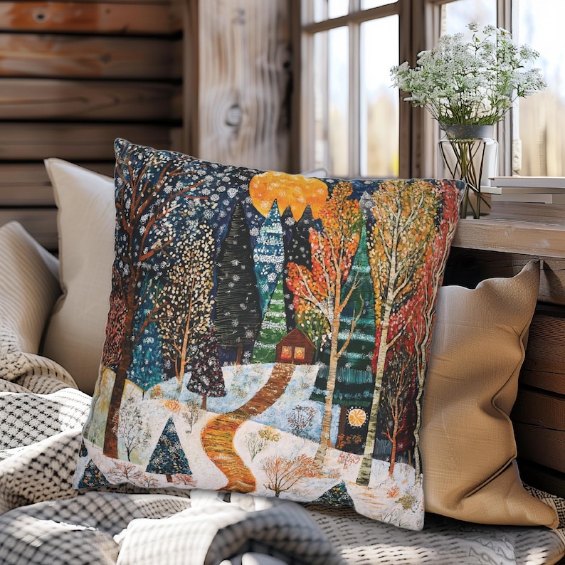 May include: A colourful throw pillow featuring a winter scene of a snowy forest with a small cabin in the distance. The pillow depicts a winding path through the trees and a bright yellow sun shining through the branches.
