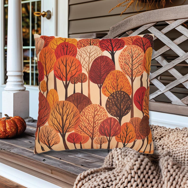 May include: A decorative throw pillow with a pattern of stylized trees in shades of orange, red, brown, and beige. The trees are arranged in a random pattern on a cream background.