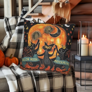 May include: A black and orange Halloween pillow with three black cats dancing around a large orange moon. The moon has a crescent moon shape on the top and the text "Hallow Moon" and "Mystical Meows" on the bottom.