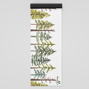 May include: A white yoga mat with a watercolor design of a row of green pine trees. The text "needle" is printed in black at the bottom of the mat.