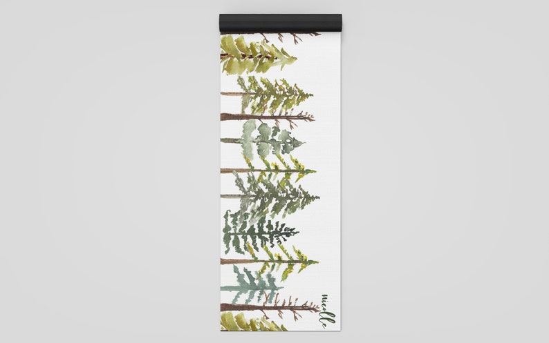May include: A white yoga mat with a watercolor design of a row of green pine trees. The text "needle" is printed in black at the bottom of the mat.