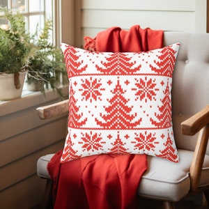 May include: Red and white cushion with a knitted Christmas tree and snowflake pattern.
