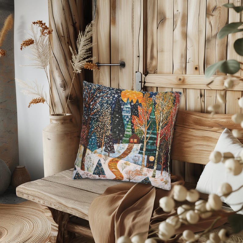 May include: A decorative cushion featuring a wintery forest scene. The cushion depicts a snowy path leading to a small cabin in the woods. The trees are adorned with colourful lights and snowflakes.