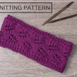 May include: A purple knitted headband with a lacy pattern. The headband is lying on a wooden surface with two knitting needles.