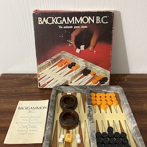 May include: A vintage Backgammon B.C. game set. The box features the game's name and a graphic of dice being thrown. The set includes a marble-patterned game board, dice, doubling cube, and game pieces in orange and black.