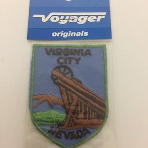 May include: A blue and green embroidered patch with the text "Virginia City, Nevada" and a depiction of a cannon.