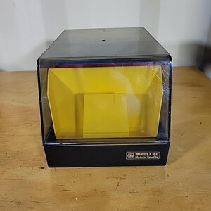 May include: A black and clear plastic MINIDEX 60 Modular ViewFile. The container has a yellow interior with a clear plastic top. The product is sitting on a wooden surface.