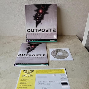 Puede incluir: Un juego completo de Outpost 2. La caja presenta un gráfico oscuro con el título del juego. Incluye la caja del juego, el manual del juego, el CD-ROM y los materiales de registro. La caja y el manual tienen el título del juego y el logotipo de Sierra.