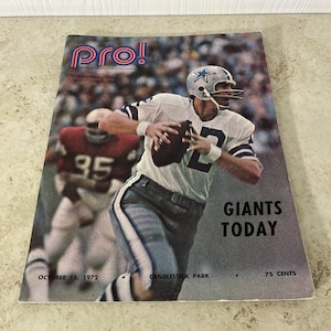 Può includere: Copertina della rivista Pro! vintage con un giocatore di football americano in uniforme bianca e blu che lancia un pallone. La copertina presenta il testo "GIANTS TODAY" e "OCTOBER 15, 1972".