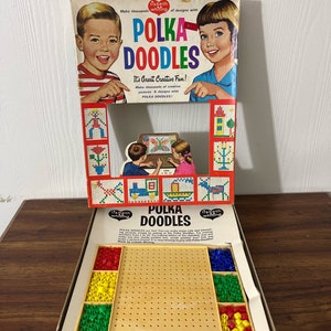 May include: A vintage Polka Doodles toy set. The box has illustrations of children and the text "Polka Doodles". The set includes a pegboard, colourful pegs, and a design guide. The box is open, revealing the contents.