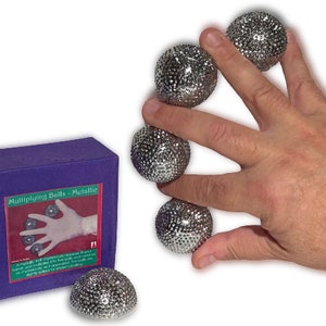 May include: A set of five silver multiplying balls. The balls are textured and have a metallic finish. The balls are shown in a hand, demonstrating the magic trick.