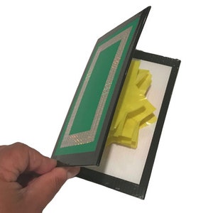 May include: A black card with a green border and a yellow starburst design inside. The card is open and the starburst is visible.